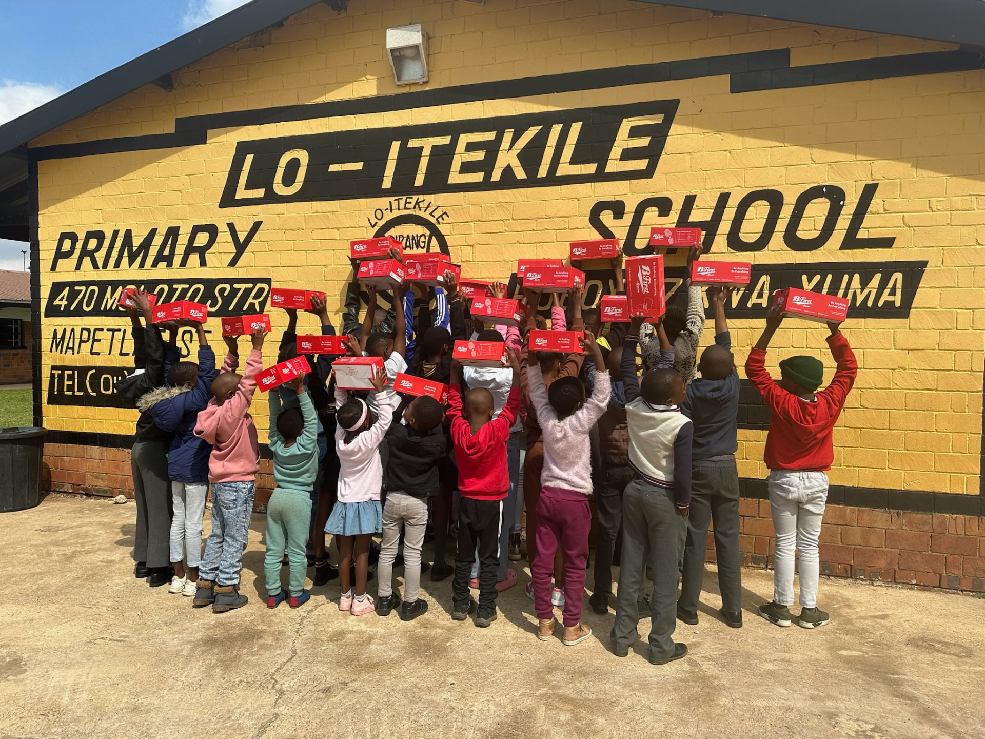 Children at Lo-Itekile Primary School holding up donated school shoes